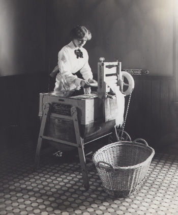 A woman using a washing machine powered by Edison storage batteries.